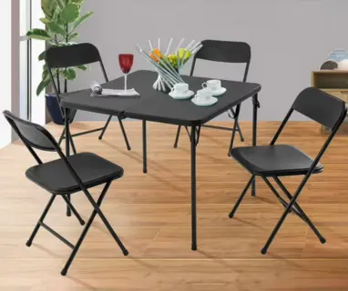 Black folding square card table surrounded by four black folding chairs on a wood floor.